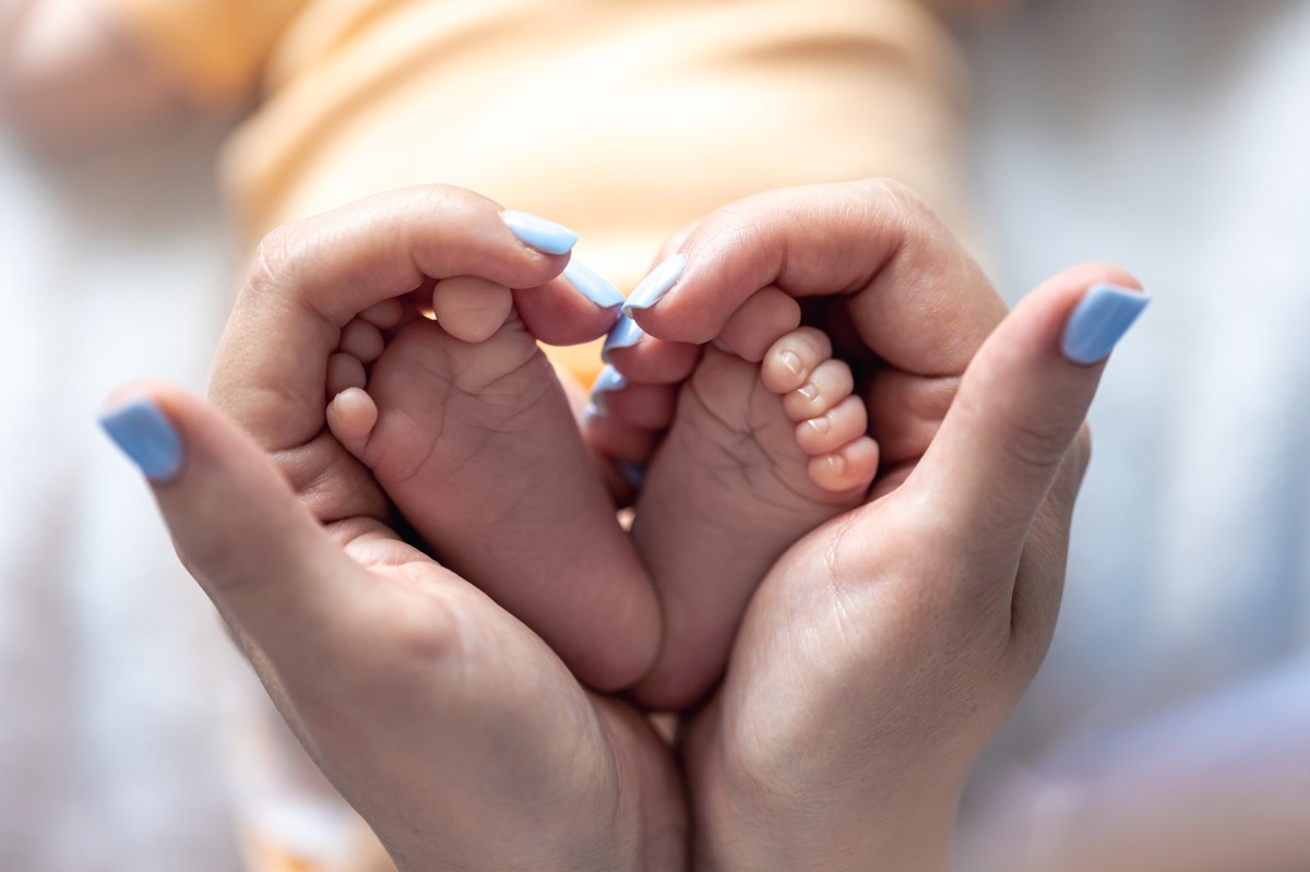 pm3mom-holds-legs-newborn-baby-her-hands-1200w.jpg